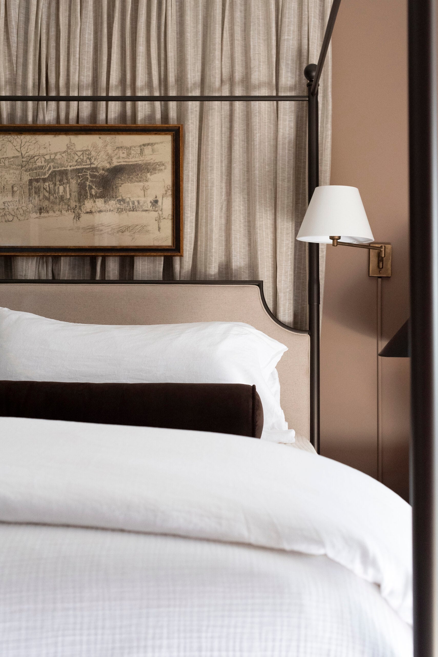 White Bedding on Bed with Brown Bolster and Curtains Behind Canopy