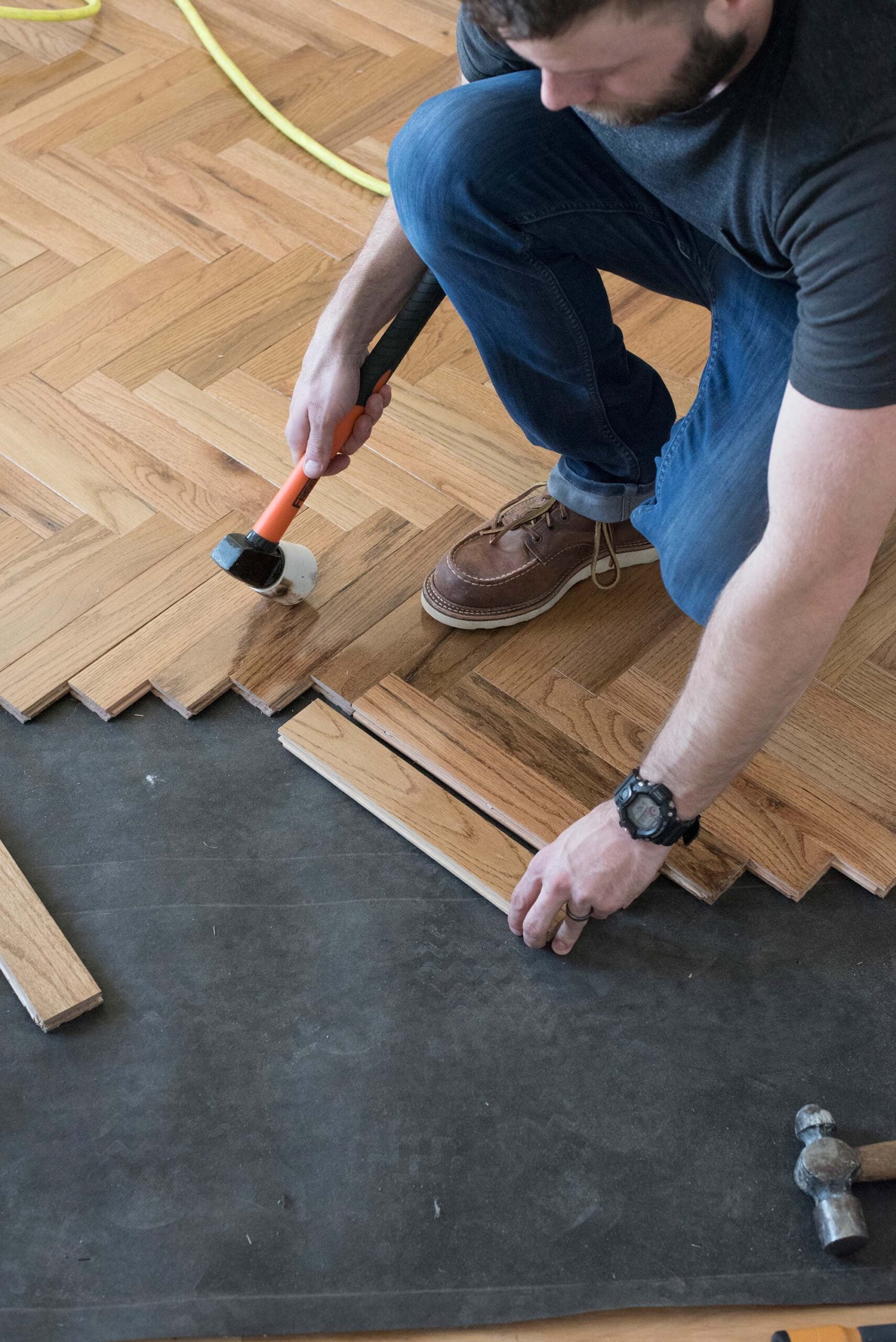 Begin installing the hardwood. Push two pieces of wood perpendicular to each other, locking the tongue-and-groove up against the jig