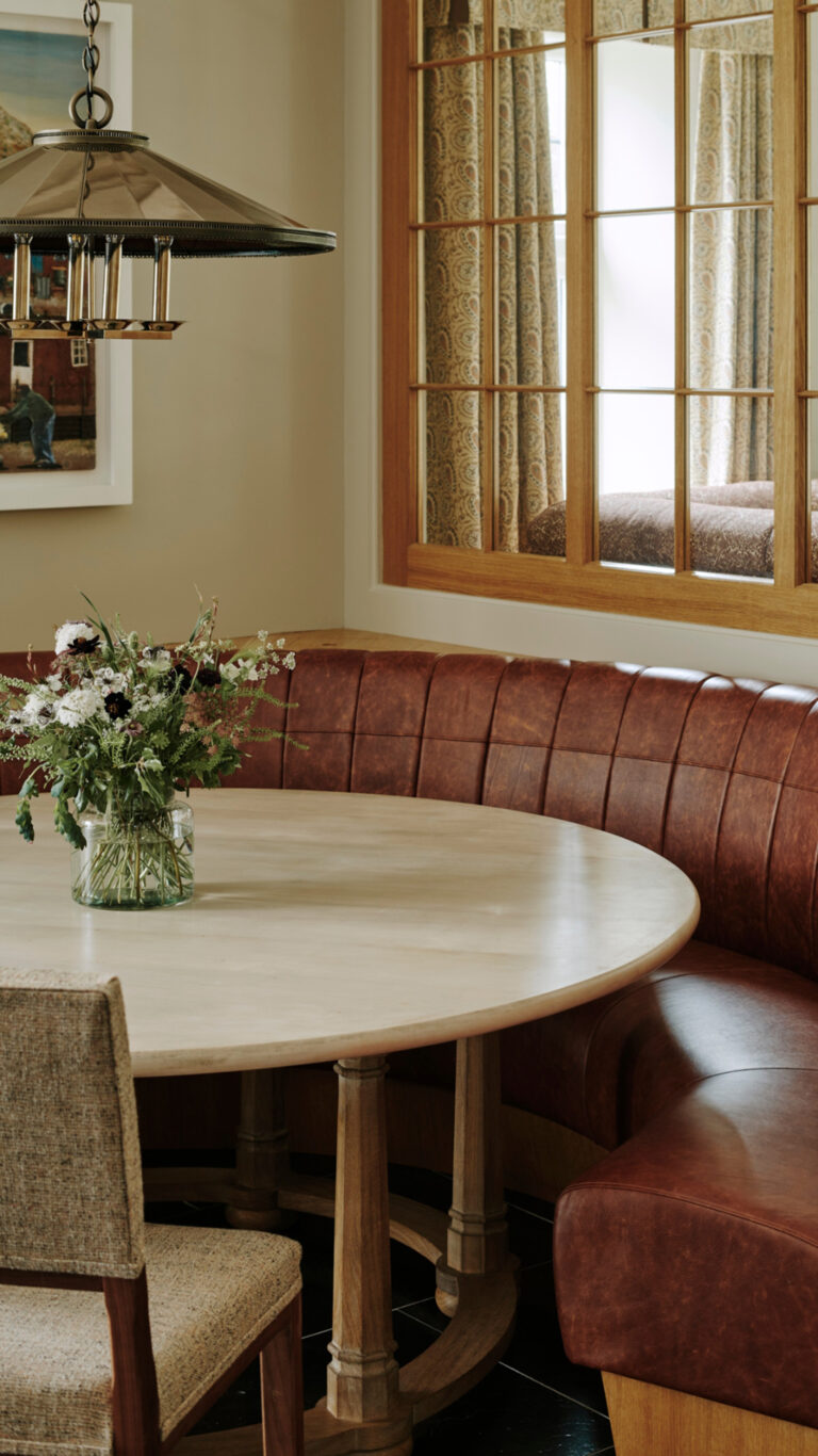 Art-deco-inspired-breakfast-nook-with-round-table-brass-chandelier-and-leather-bench