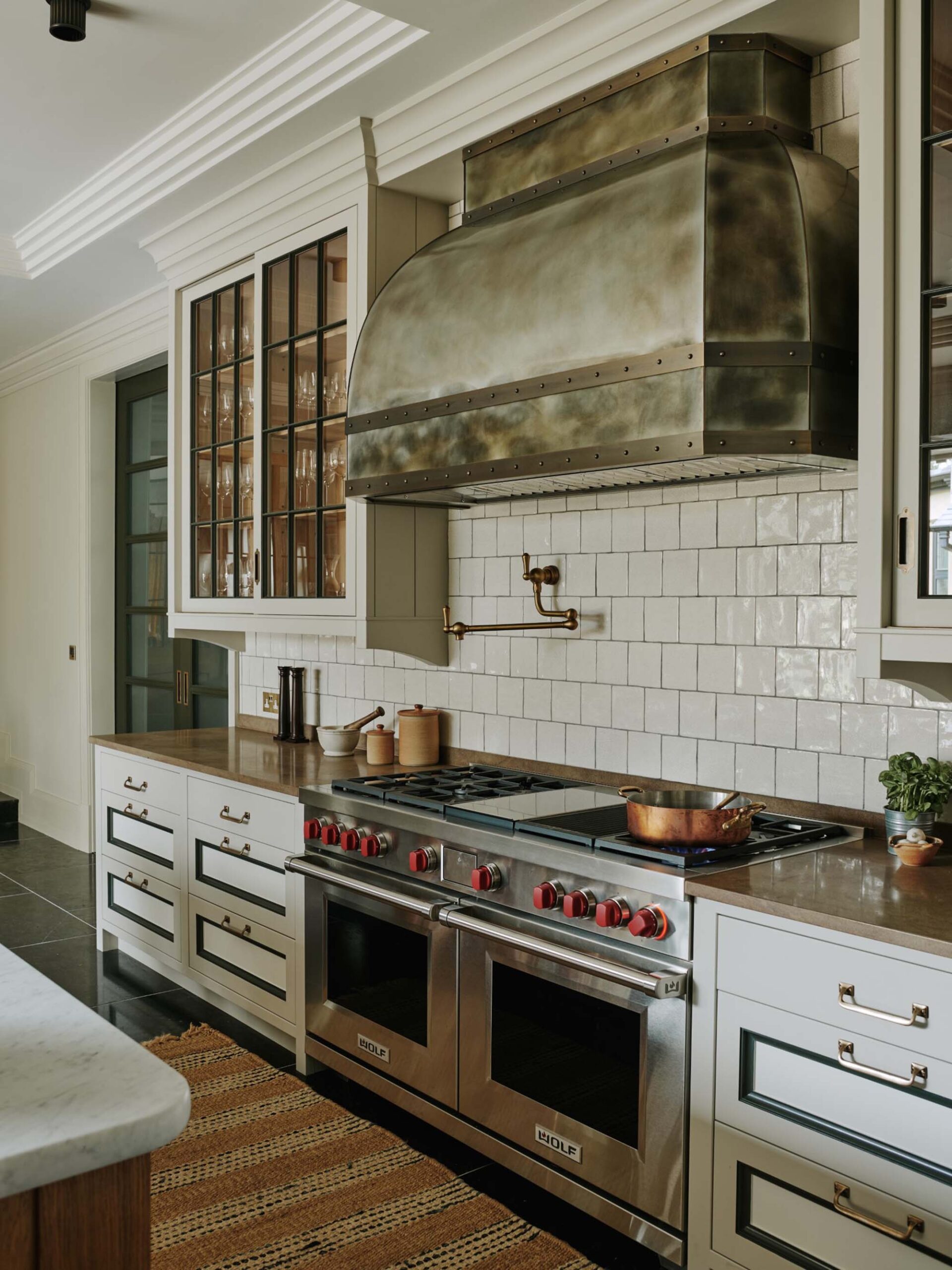 Double-Stainless-Ranges-with-Silver-Hood-and-Inset-Cabinetry-with-brown-countertops