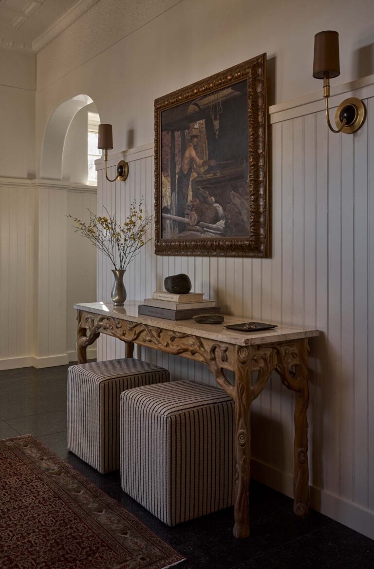 ENTRYWAY-table-with-two-ottomans-flanked-by-sconces-and-artwork