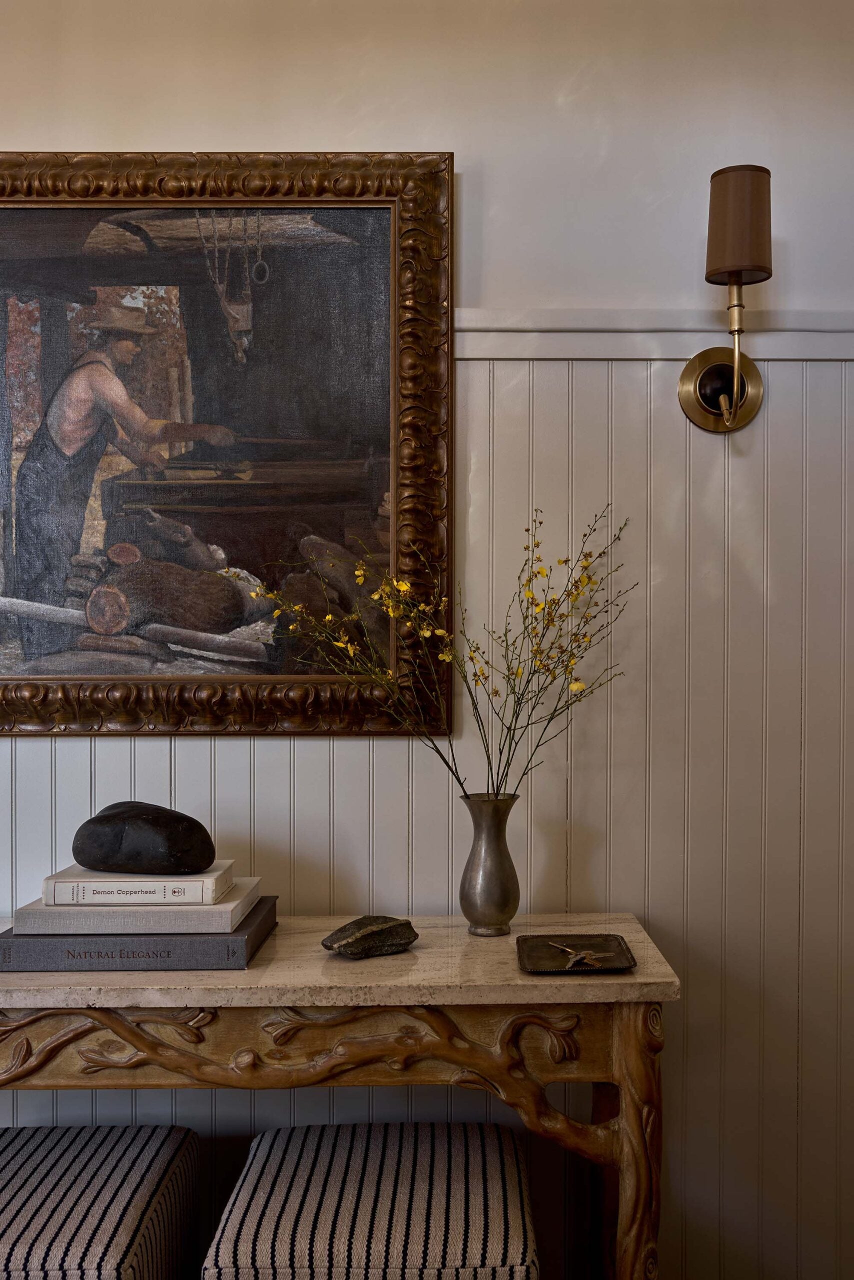 ENTRYWAY_table-with-ottomans-and-art-flanked-by-sconces