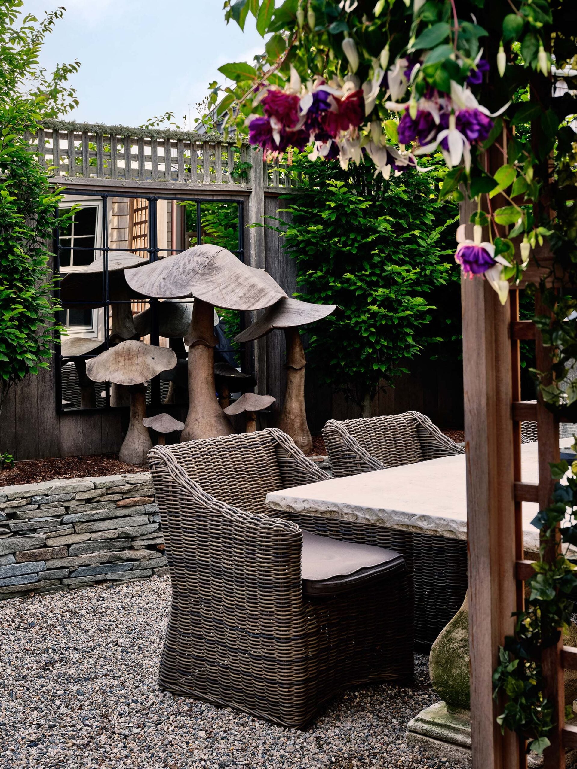 KristinPaton-Nantucket Outdoor Dining Area Cement Table Wicker Chairs Mushroom Sculpture Purple Flowers