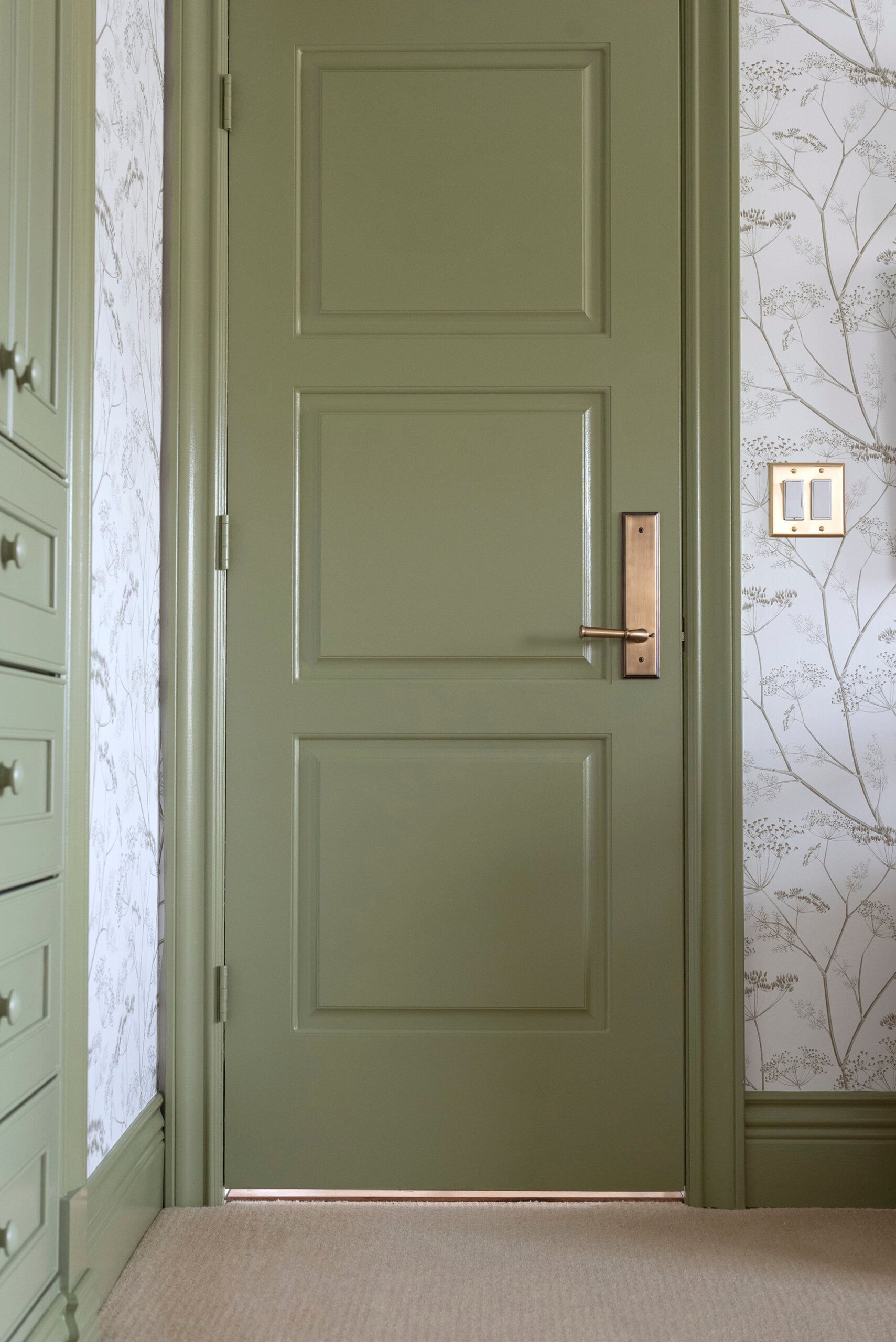 Brass Door Hardware on Green Nursery Door with Floral Wallpaper and Wool Carpet