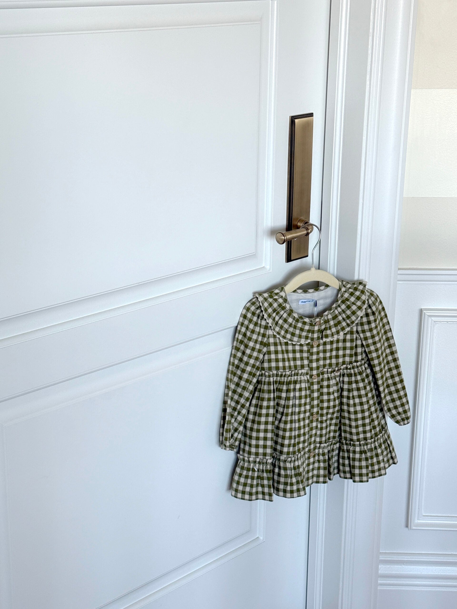 Sweet Gingham Baby Dress Hanging on Brass Doorknob