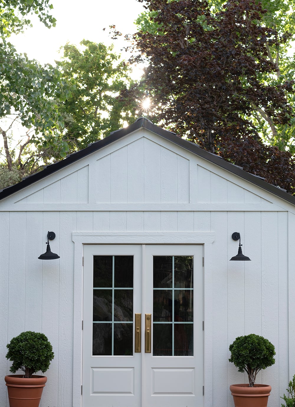 White Storage Shed with Two Terracotta Planters and Boxwoods