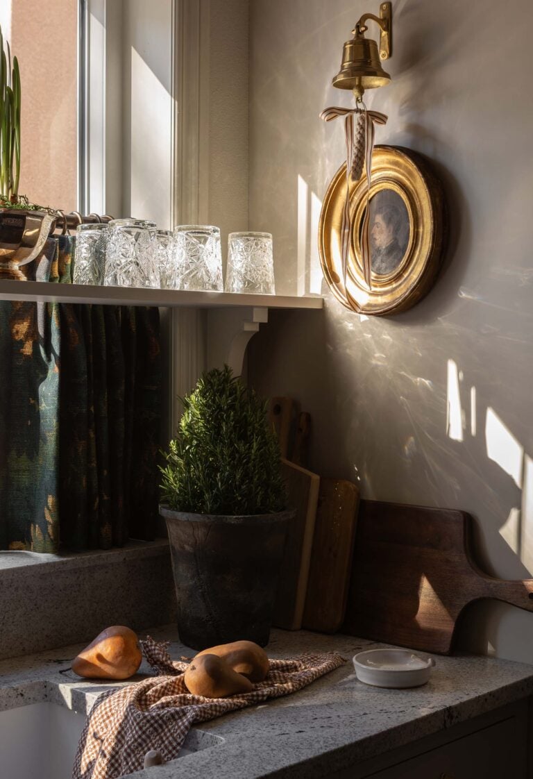 Oho Interiors-Carriage House-Kitchen Sink with dinner bell artwork cafe curtains open shelving for water glasses
