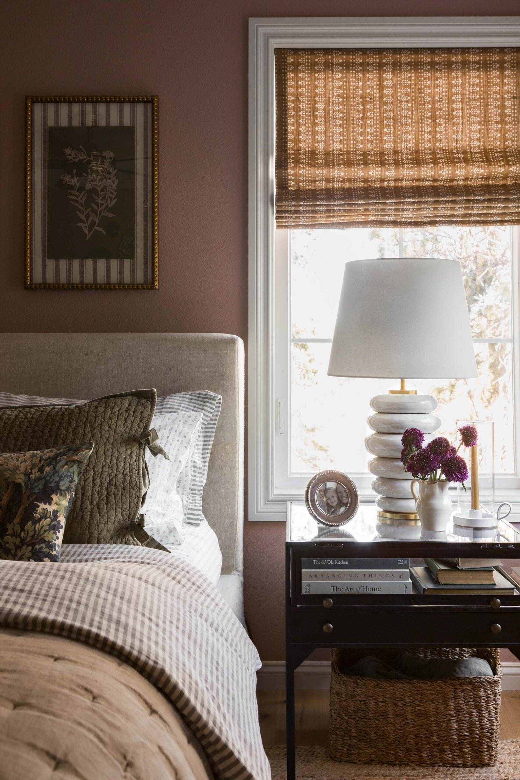 Oho Interiors-Carriage House-Nightstand with Lamp and photo in front of window with woven shade