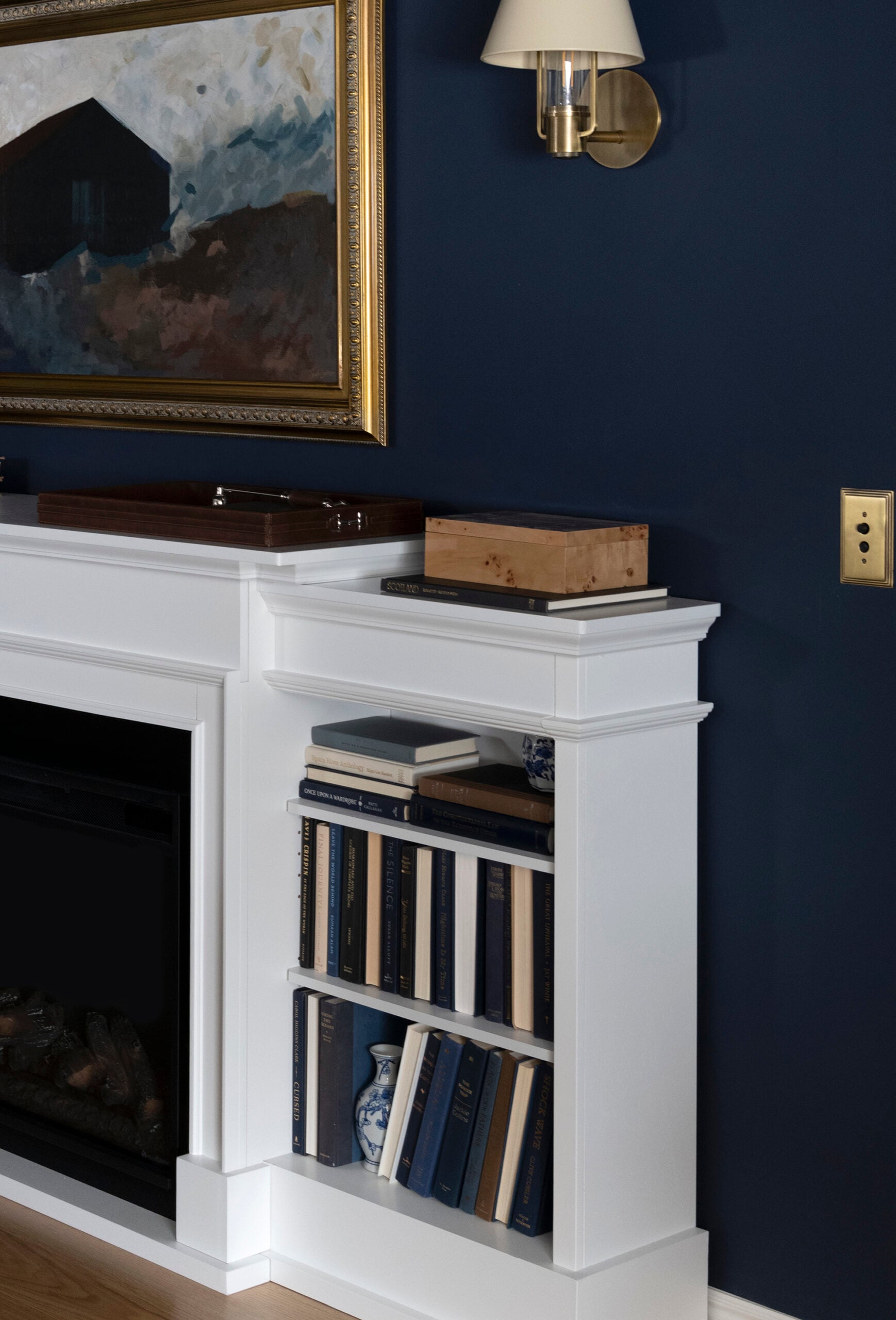 Brass Push Button Light Switch Next to Sconce on Navy Fireplace Wall