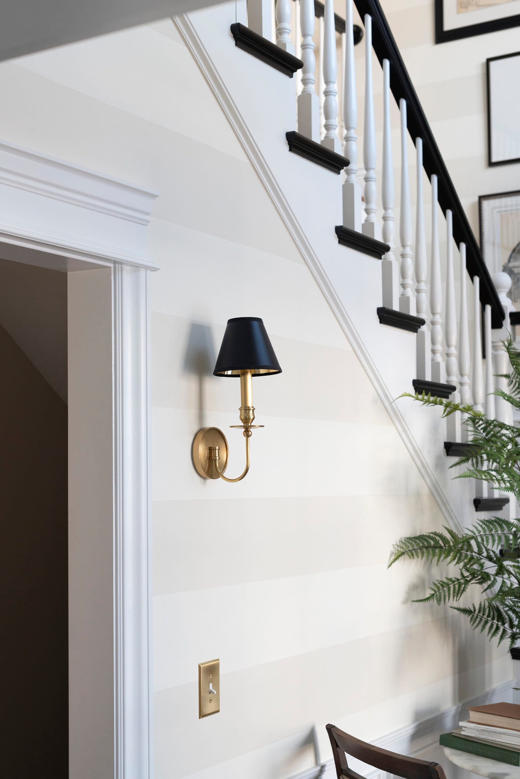 Brass Sconce with Black Shade Against Striped Wall