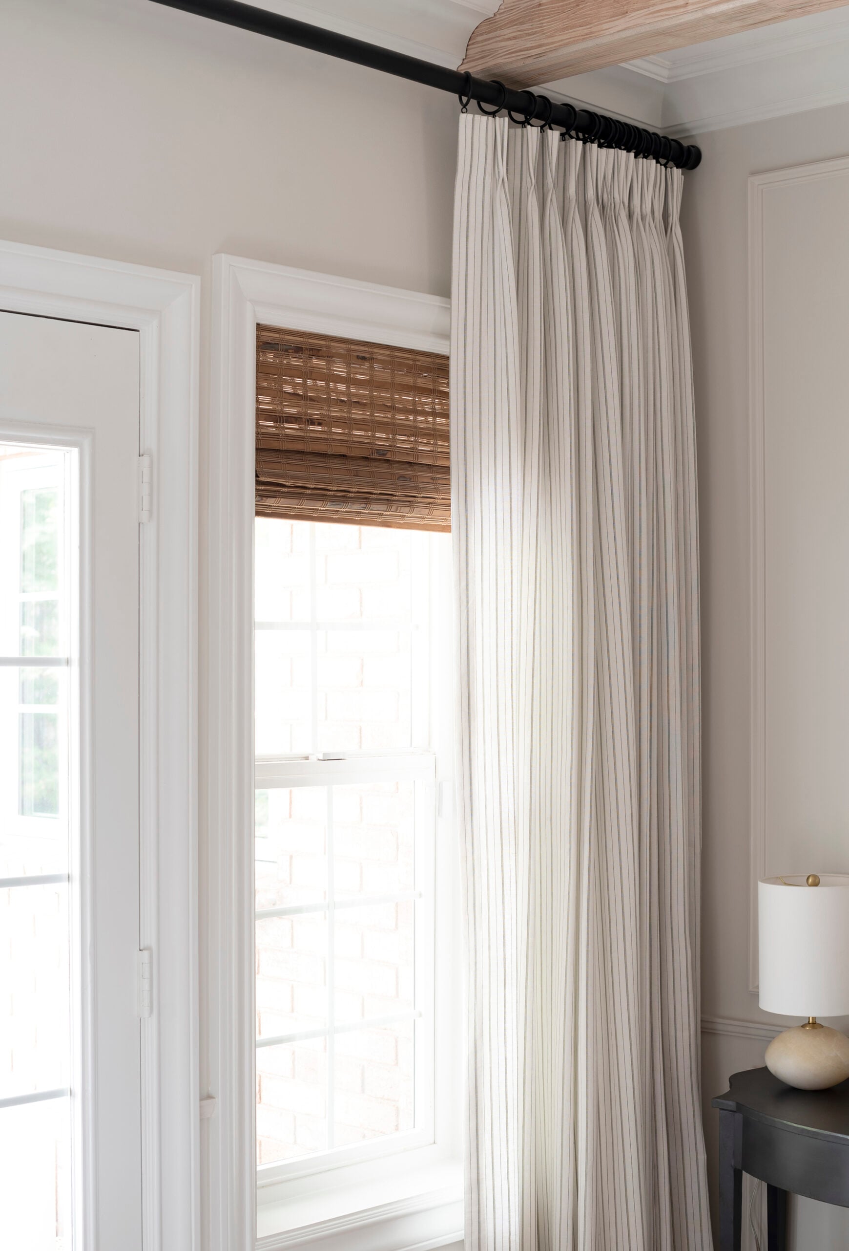 Woven Wood Roman Shade Layered behind Pleated Drapery Panels