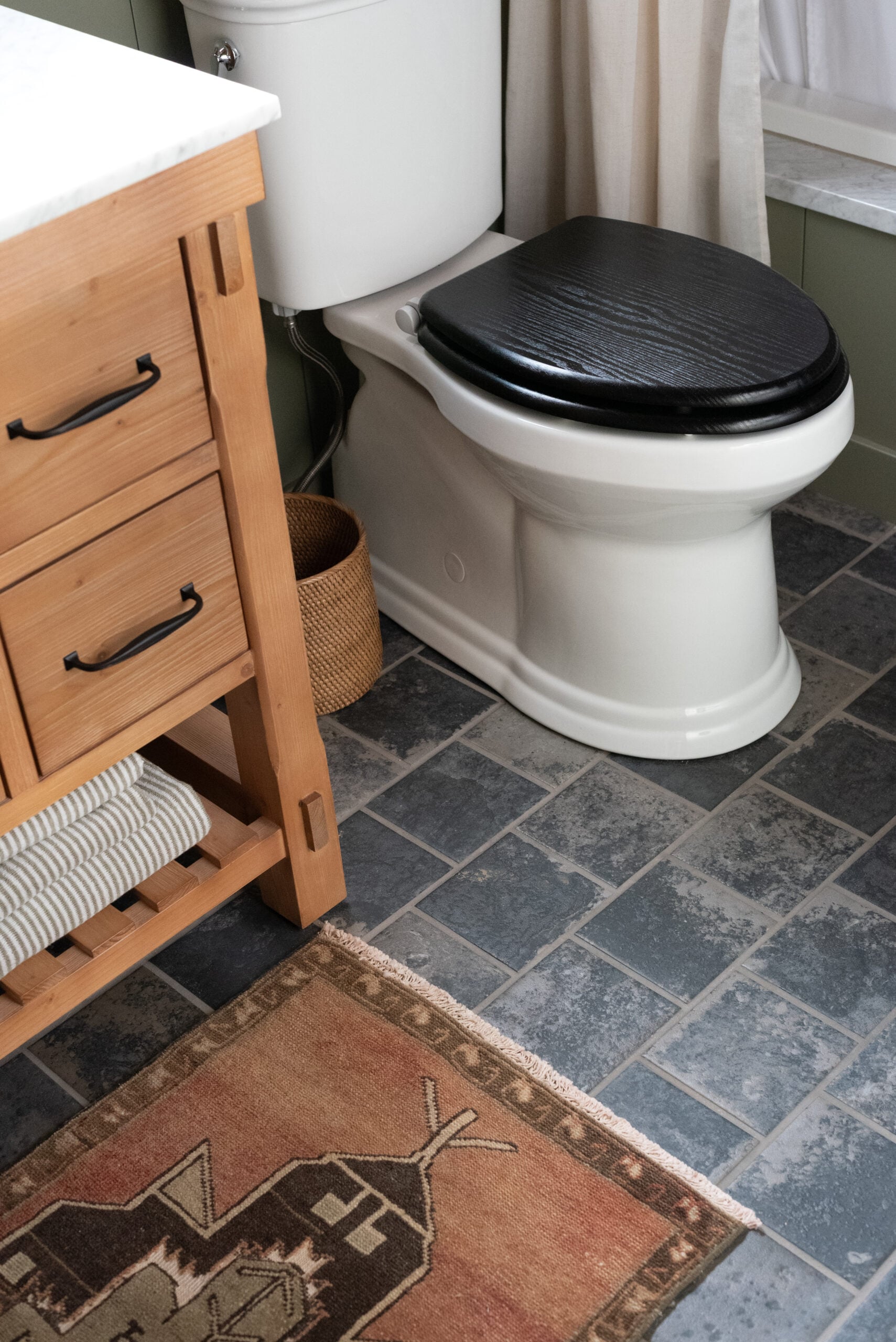 Kohler Batten Toilet in Cabin Bathroom with Vintage Rug and Wood Vanity