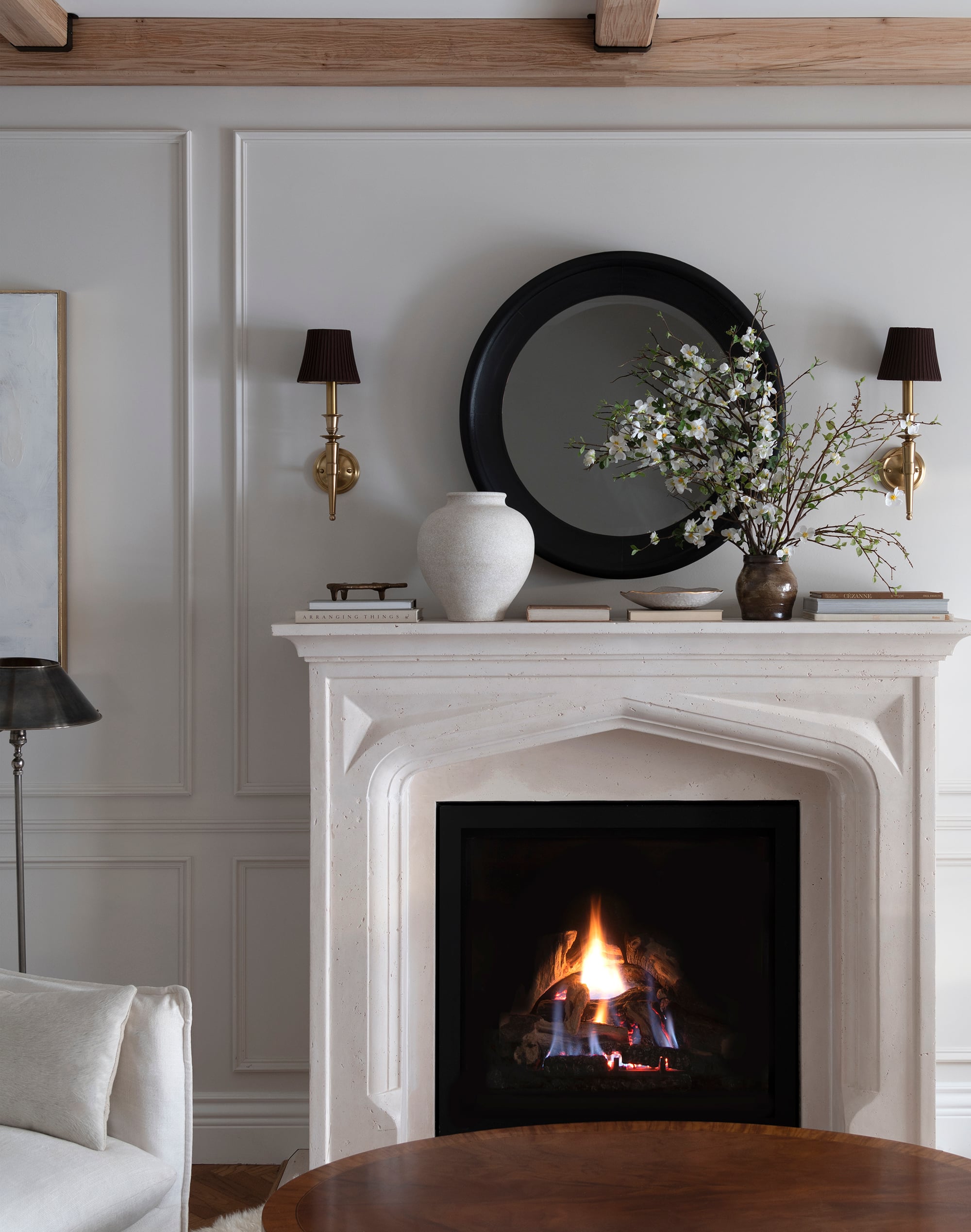 Neutral Limestone Fireplace with Sconces and Mirror Above Mantel
