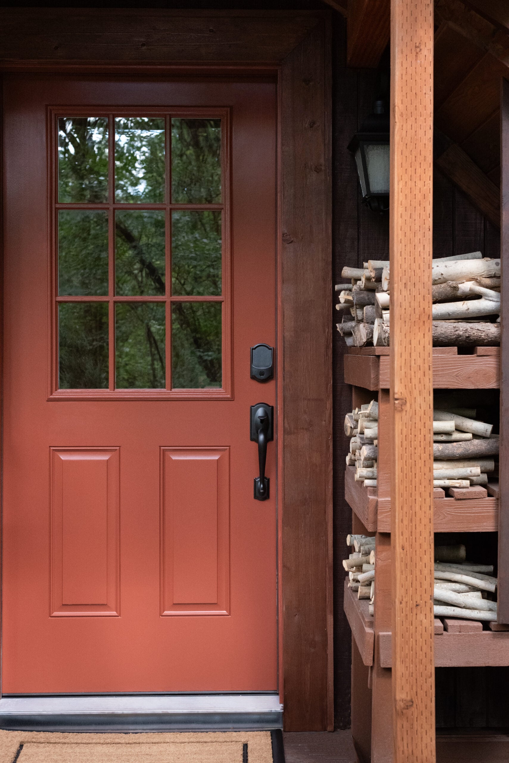 Red Cabin Front Door with Stacked Wood and Porch Light