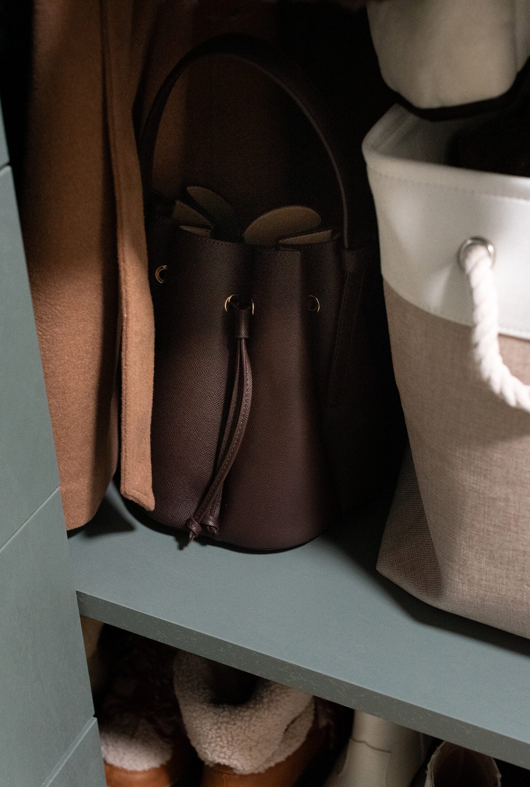 Brown Bucket Bag Purse for Fall Next to Wool Coat in Closet