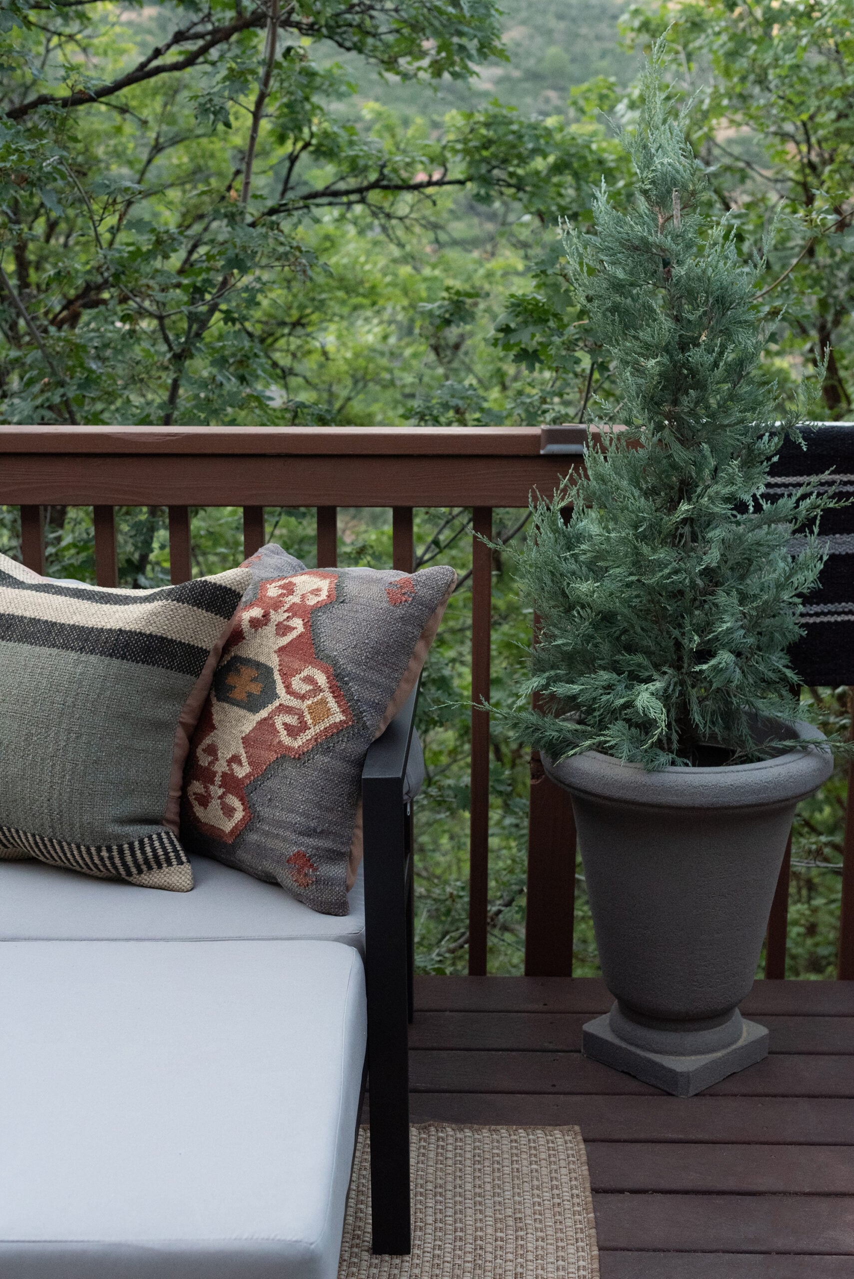 Geometric Aztec Pillows on Outdoor Sofa Next to Planter Juniper Tree