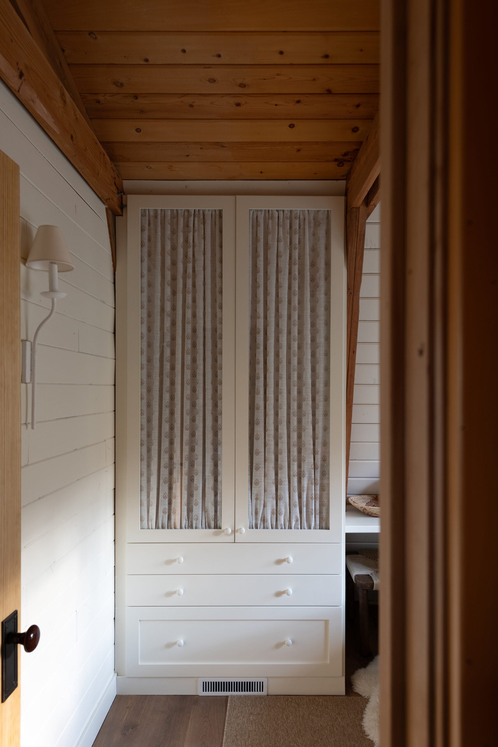 Custom Built-In Storage Cabinet with Fabric Panel Doors in Cabin Bedroom